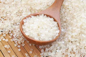 Rock sugar and wooden spoon on bamboo background