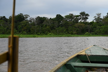 Small tourist boat on the stormy, rough Amazon river near the Colombia / Peruvian border, with pink...