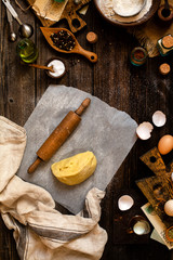 Overhead shot of homemade dough and rolling pin on baking paper on rustic table 