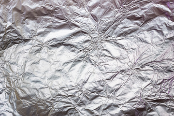Crumpled aluminum foil background or texture. Wavy and folded deformation