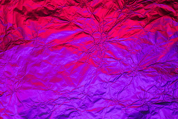 Purple red deformed background made of neon lights foil. Trendy duotone texture