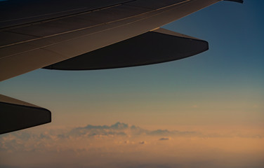 Wing of plane over blurred mountain cover with white snow. Airplane flying. Scenic view from airplane window. Commercial airline flight. Plane wing. Flight mechanics concept. International flight.