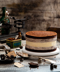 Homemade tasty black cookie cake with cheesecake between biscuit chocolate layers and cream