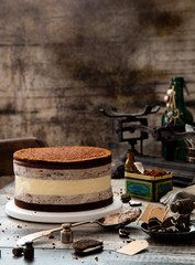 Homemade tasty black cookie cake with cheesecake between biscuit chocolate layers and cream