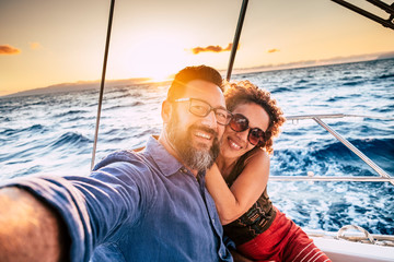 Happy and cheerful people enjoying the travel and trip on a sail boat with ocean and sunset...