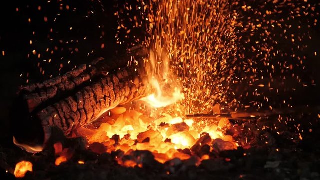 Wrought rose is placed in a shiny forge with spotty fire in a blacksmith workshop 