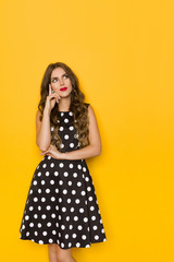 Beautiful Young Woman In Black Coctail Dress In Polka Dots Is Looking Away And Thinking