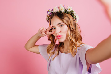 Ecstatic caucasian short-haired lady expressing positive emotions. Indoor close-up photo of magnificent blonde girl making selfie.