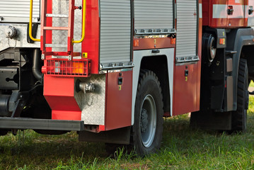 Fire truck close-up. Element of a body of a red car. Truck on the background of nature and grass.