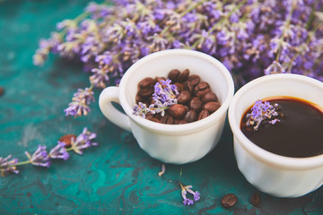 Coffee, coffee grain in cups and lavender flower on green background