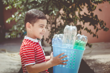 Plastic pollution. Little boy collected plastic bottles and holding recycling bin. Free space