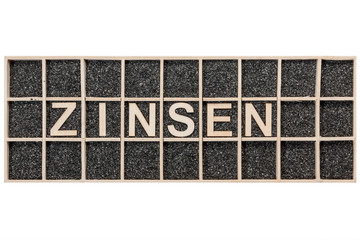 Wooden word ZINSEN on black sand rectangular