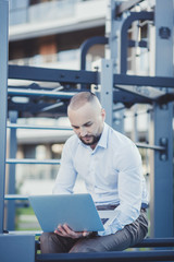 business man in shirt sitting with laptop outdoors