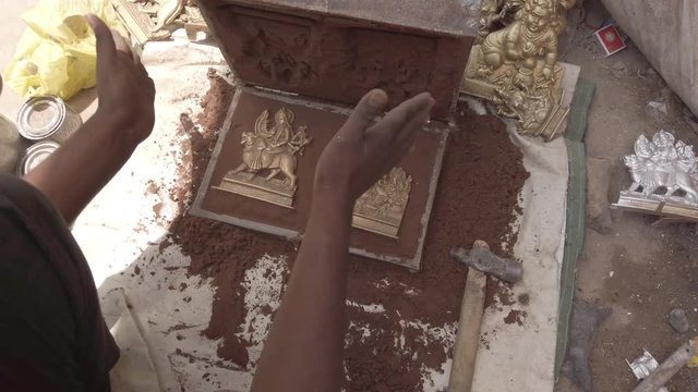 Indian metal workers casting Hindu God and Goddess idols using recycled up-cycled melted metal from everyday objects at a makeshift roadside workshop in India- 4k slow-motion handheld stabilized 