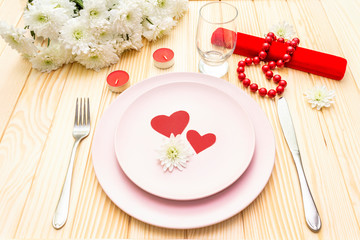 Romantic dinner concept. Valentines day, 8th march or wedding. Table setting, love hearts, gift and flowers. On wooden background