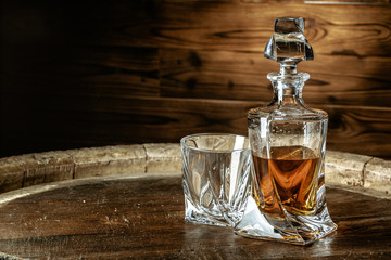 A bottle of cognac and glass on a brown wooden background. Brandy