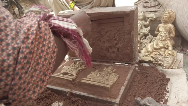 Indian metal workers casting Hindu God and Goddess idols using recycled up-cycled melted metal from everyday objects at a makeshift roadside workshop in India- 4k slow-motion handheld stabilized 
