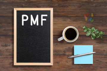 PMF written on letter board next to sticky notes and coffee on wooden background