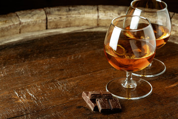 Two glasses of bourbon or scotch, or brandy and pieces of dark chocolate