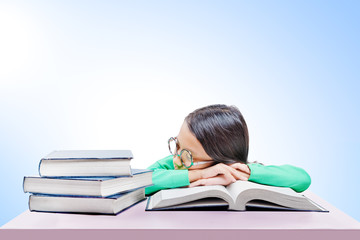 Asian cute girl with glasses fall asleep on book on the desk