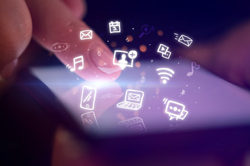Fototapeta premium Finger touching phone with hologram application icons and dark background 