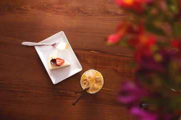 Abstract background with cake with strawberries and cold cup of coffee on a wooden table. Copy space for your text. Flat lay, top view. 