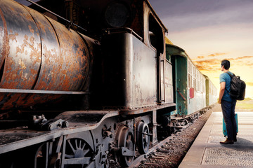 Rear view of asian man with suitcase bag and backpack standing and waiting a train on station