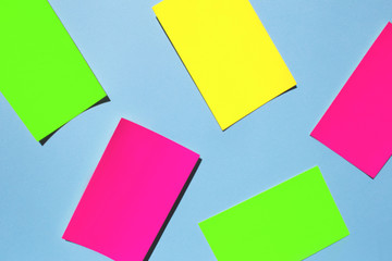 Neon colorful sticky note paper on blue background. Copy space for your text. Flat lay, top view. 