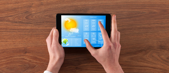 Man hand checking weekly weather forecast on tablet
