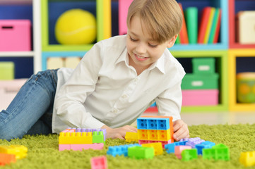 Cute little boy playing with colorful plastic blocks
