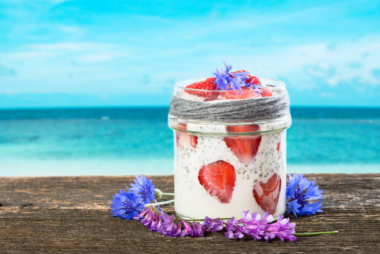 Healthy smoothie with chie seeds and fresh strawberries on rustic wood plank with tropical sea background
