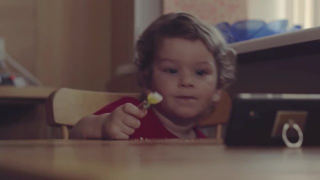 Technology generation. Happy childhood. Little boy child dirty mouth drooling, eating breakfast playing with mobile phone at table. Home.