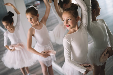 Group of little ballerinas girls doing exercises in dance school