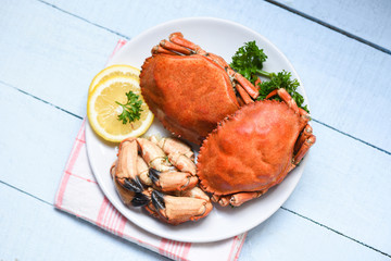 Cooked crab on white plate and wooden background - Seafood boiled red stone crab claw with herb and spices