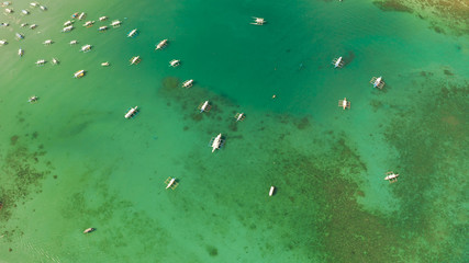 Many boats in the turquoise lagoon near city El nido, aerial view. Seascape with blue bay and boats view from above. Palawan, Philippines. traditional Filipino wooden outrigger boat called a banca