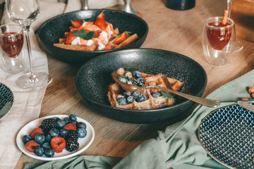 Belgian waffles with berries, ice cream and chocolate. Breakfast table setting. Morning lifestyle concept.