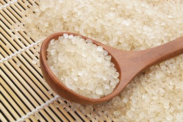 Wooden spoon and brown rock sugar bamboo background