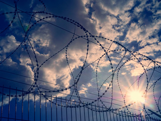 Barbed wire against the sky and the sun