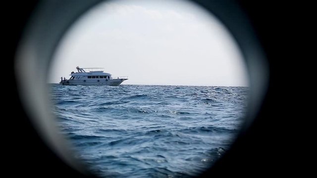 The boundless sea through the porthole of a moving ship