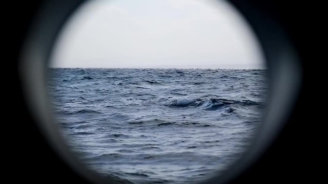 The boundless sea through the porthole of a moving ship