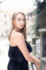 Beautiful woman with blonde hair standing on the stairs and looking at camera over her shoulder. Lifestyle photography.