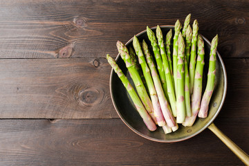 Asparagus in rustic pan on wooden background. Top view