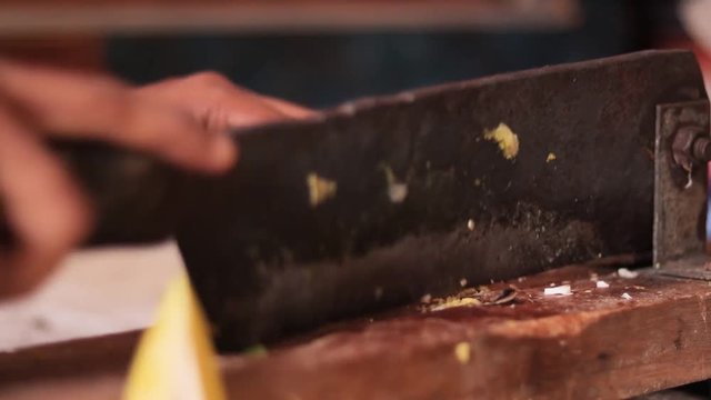 Closeup of Hands cutting ripe Mango for making Pickle In India with Indian vegetable cutter.