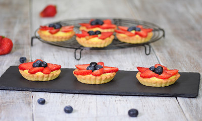 Summer berry tartlets with cream and fresh berries. Healthy summer pastry dessert for party.