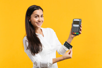 Smiling young woman holding wireless modern bank payment terminal to process and acquire credit...