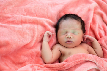 Newborn baby girl sleeping in pink cloth.