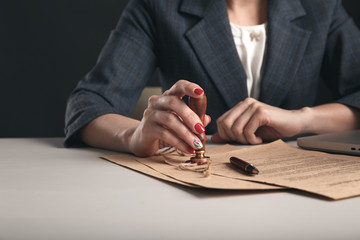 Woman notary with paper documents and pen sitting at the desk