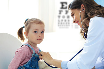 Little girl at the doctor for a checkup. Doctor woman auscultate the heartbeat of the child.
