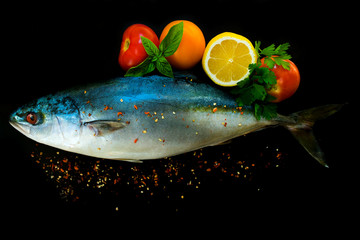  Fresh sea fish tuna in with vegetables and spices on a black background. Close-up.