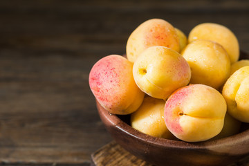Apricots in a wooden bowl on a wooden table. rustic style